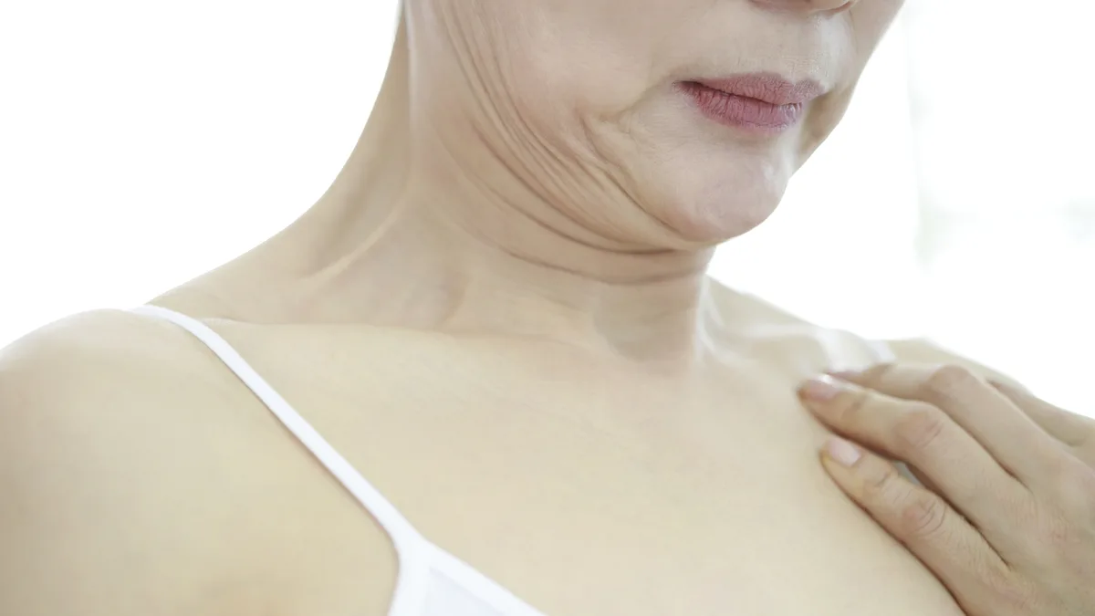 목 앞쪽과 쇄골 부위에 손을 얹고 있는 중년 여성
