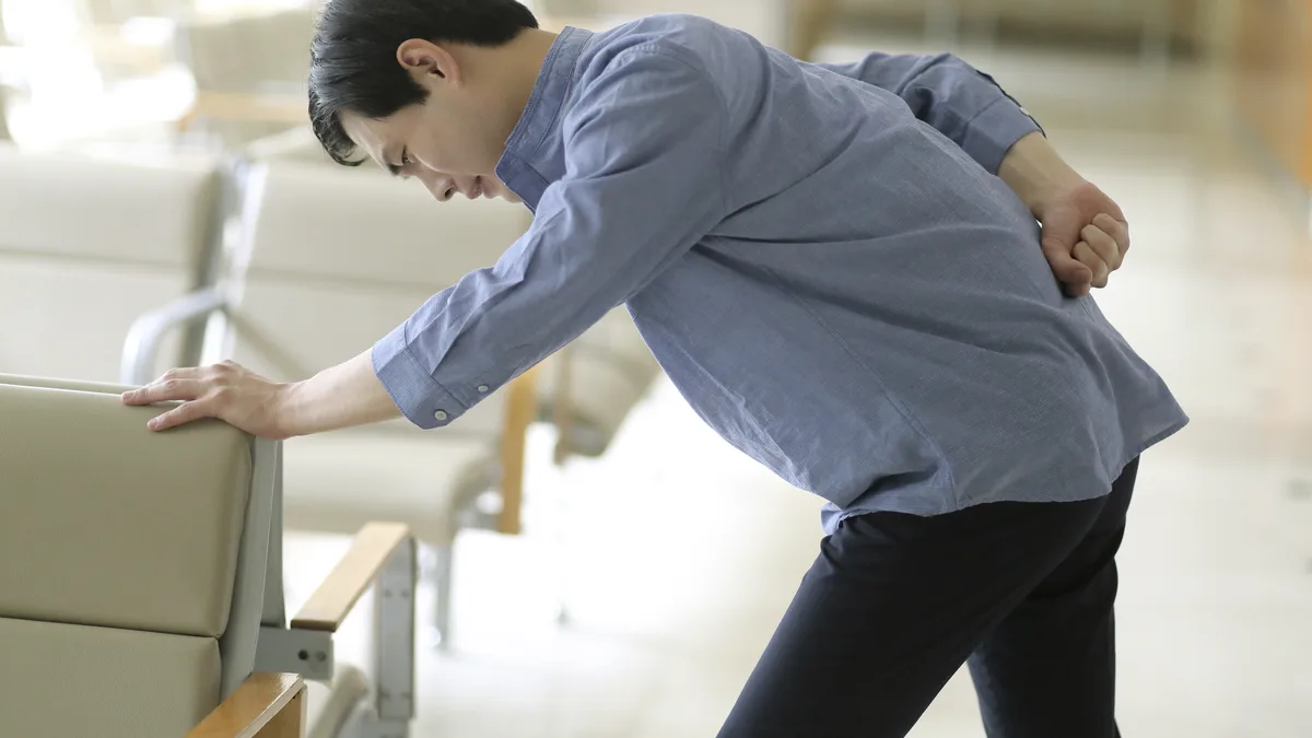 속이 불편해 몸을 숙이고 배를 짚고 있는 남성